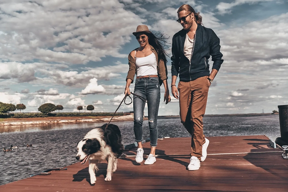 Couple walking with a dog on a dock